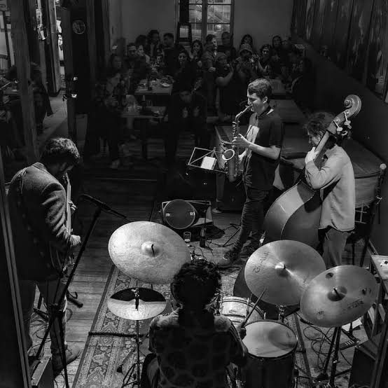 Cuarteto de jazz tocando en un bar lleno, en blanco y negro